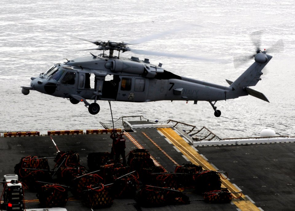 US Navy 110315-N-3729D-119 Sailors aboard the amphibious assault ship USS Peleliu (LHA 5) hook a cargo net of ammunition to an MH-60S Sea Hawk heli