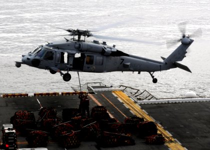 US Navy 110315-N-3729D-119 Sailors aboard the amphibious assault ship USS Peleliu (LHA 5) hook a cargo net of ammunition to an MH-60S Sea Hawk heli