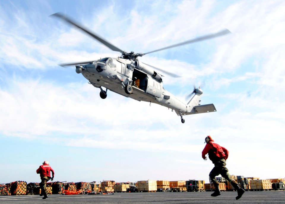 US Navy 110316-N-3729D-280 Sailors run to attach a pole pendant to an MH-60S Sea Hawk helicopter aboard the amphibious assault ship USS Peleliu (LH