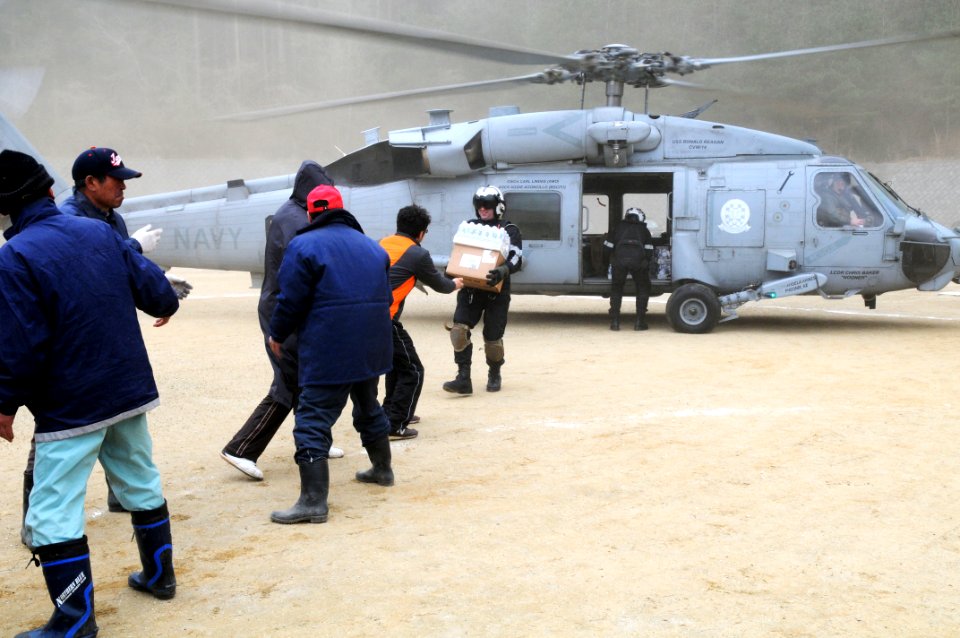 US Navy 110315-N-IC111-121 Naval Air Crewman 2nd Class Zack DelCorte hands bottled water to a Japanese citizen