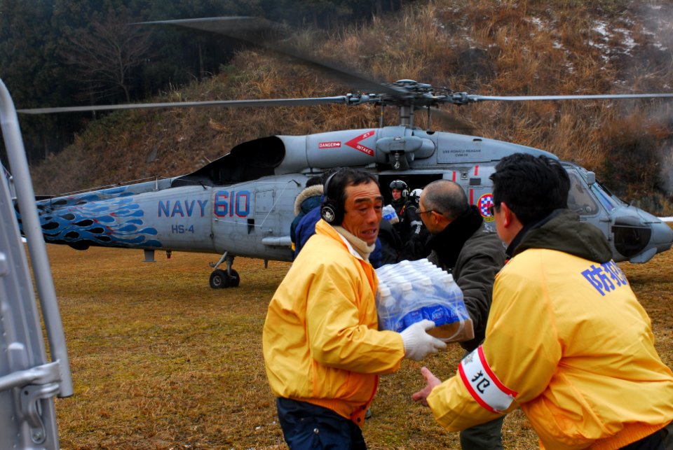 US Navy 110316-N-SB672-114 Japanese citizens unload food and water from an HH-60H Sea Hawk helicopter assigned to the Black Knights of Helicopter A