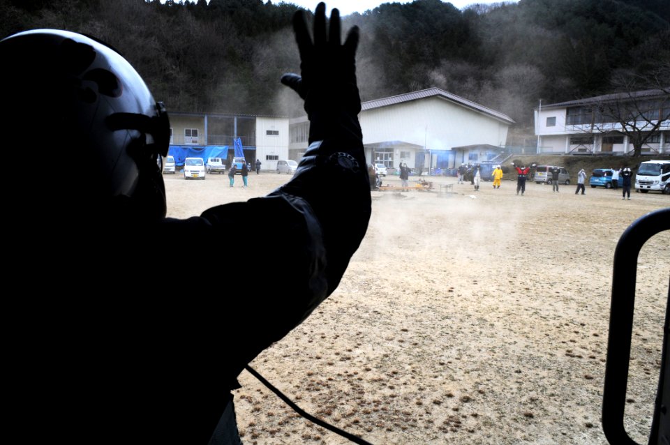 US Navy 110315-N-IC111-466 Chief Naval Air Crewman Steven Sinclair waves to Japanese citizens after delivering supplies during tsunami relief effor