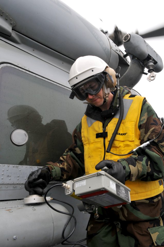 US Navy 110320-N-DM338-219 Machinist's Mate 1st Class Lucas Kasper, from Yorba Linda, Calif., scans an SH-60B Sea Hawk helicopter assigned to the W
