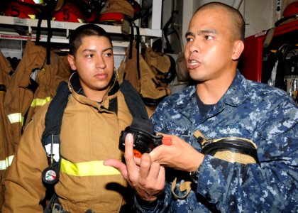 US Navy 110317-N-BK435-041 Damage Controlman 2nd Class Jesuric Incoy, right, assigned to the submarine tender USS Frank Cable (AS 40)