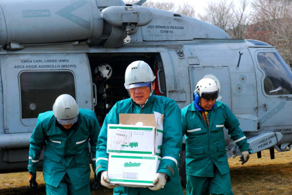 US Navy 110318-N-SB672-477 Japanese disaster relief workers carry humanitarian supplies delivered by a U.S. Navy helicopter crew