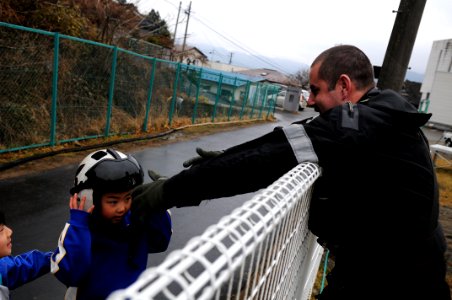US Navy 110321-N-IC111-206 Naval Air Crewman 2nd Class Chris Tautkus gestures to a Japanese child to return his helmet