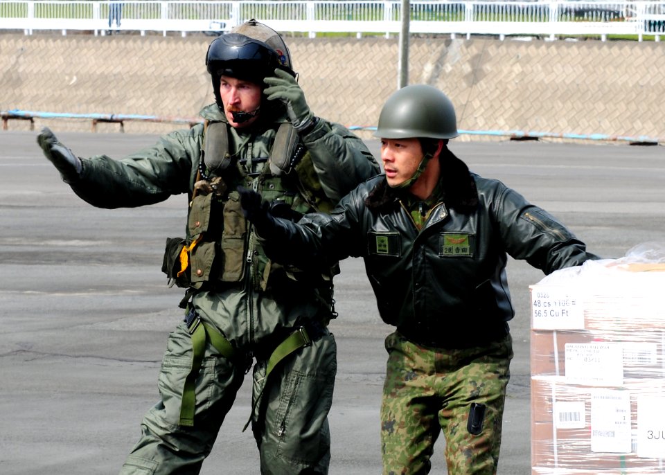US Navy 110322-N-5538K-627 Gunnery Sgt. Sam Carnes, left, and a member of the Japan Maritime Self-Defense Force direct the movement of humanitarian