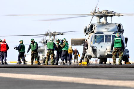 US Navy 110322-N-DM338-120 Sailors and Marines load food and humanitarian assistance supplies onto an SH-60B Sea Hawk helicopter