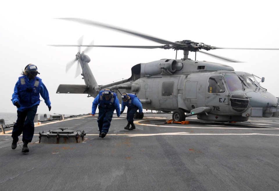 US Navy 110320-N-8288P-304 Sailors aboard USS Fitzgerald (DDG 62) run away from an SH-60 Sea Hawk helicopter after applying landing chocks during f