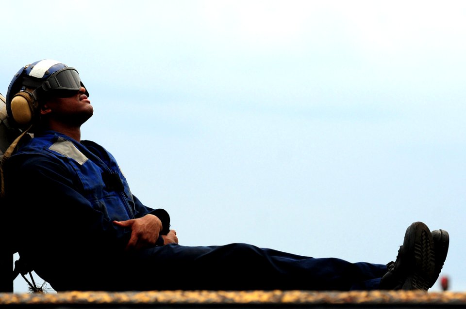 US Navy 110322-N-RC734-011 Boatswain's Mate Seaman Charles Henderson takes a break before flight operations aboard the amphibious dock landing ship