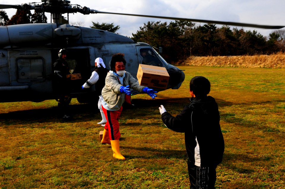 US Navy 110322-N-UO379-304 Japanese citizens unload humanitarian assistance supplies from an SH-60F Sea Hawk helicopter