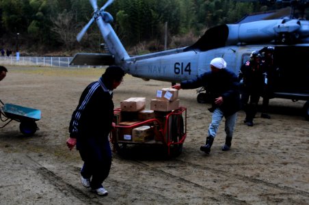 US Navy 110322-N-UO379-234 Local residents and naval air crewmen move medical supplies from an SH-60F Sea Hawk into a relief shelter