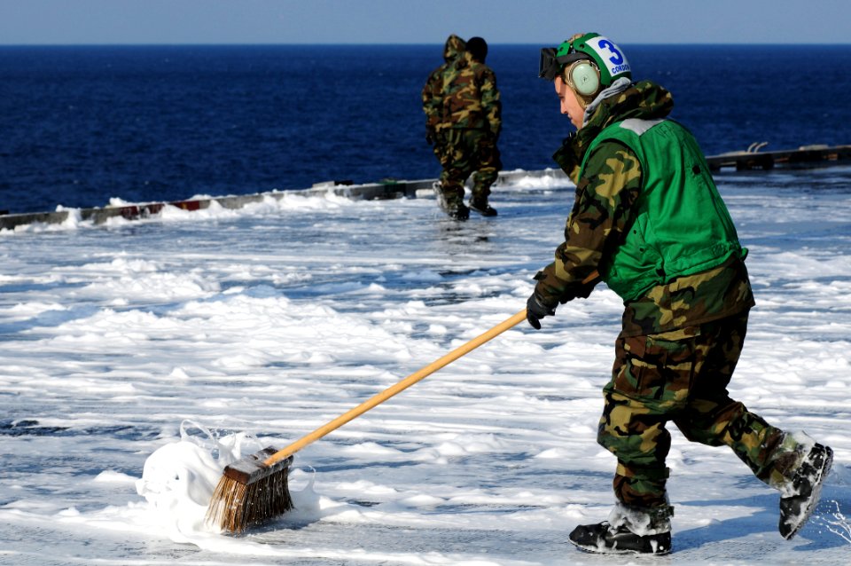 US Navy 110323-N-IC111-533 Aviation Electronics Technician Airman Ryan Cordova, from Albuquerque, N. M., scrubs the flight deck after a countermeas