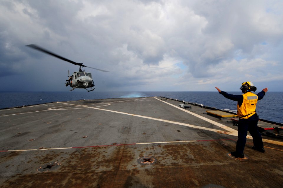 US Navy 110323-N-RC734-144 Boatswain's Mate 3rd Class Leshea Isom, from Newark, N.J., signals the pilot of a UH-1 Huey helicopte