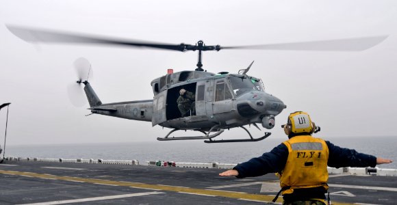 US Navy 110320-N-9950J-149 Aviation Boatswain's Mate (Handling) Airman Steven Robinson directs the lift off of a UH-1N Huey helicopter aboard USS E