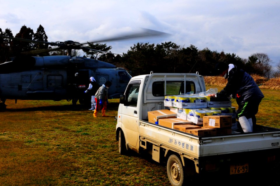US Navy 110321-N-UO379-356 Local residents unload food and humanitarian assistance supplies from an SH-60F Sea Hawk helicopter