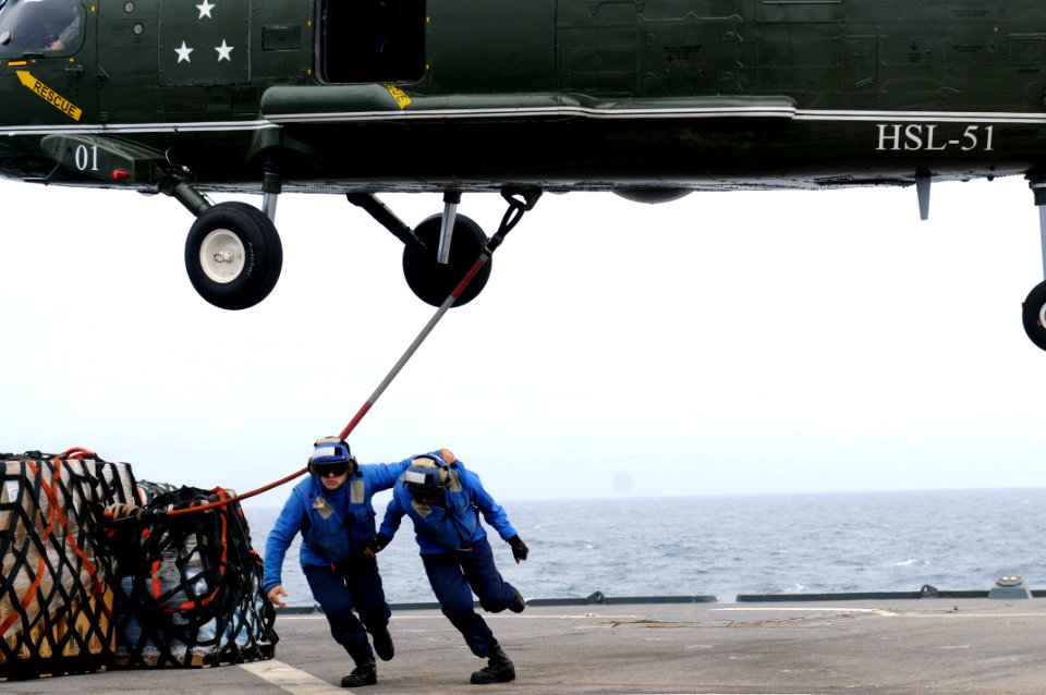 US Navy 110321-N-4031K-555 Religious Programs Specialist Seaman Matthew Clinton and Seaman Nicholas Constable run after hooking a cargo strap to an