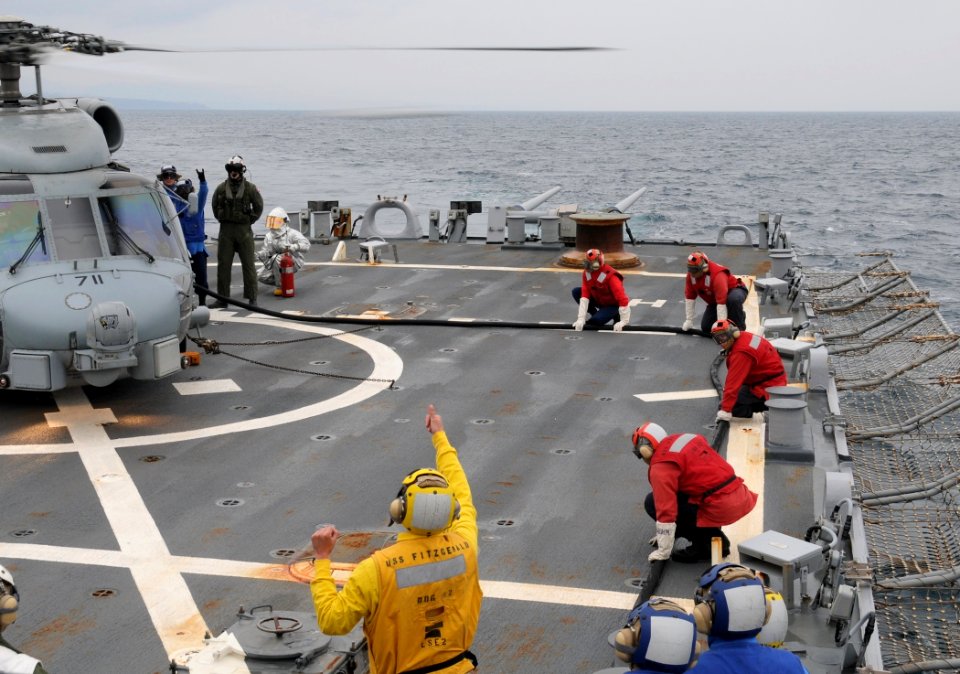 US Navy 110321-N-8288P-108 Sailors signal to each other while fueling an SH-60 Sea Hawk helicopter aboard the Arleigh Burke-class guided-missile de