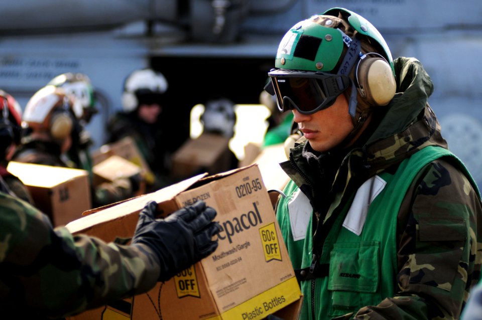 US Navy 110322-N-IC111-085 Aircrew Survival Equipmentman Airman Yuanfu Wu, from San Francisco, loads humanitarian assistance supplies onto an SH-60