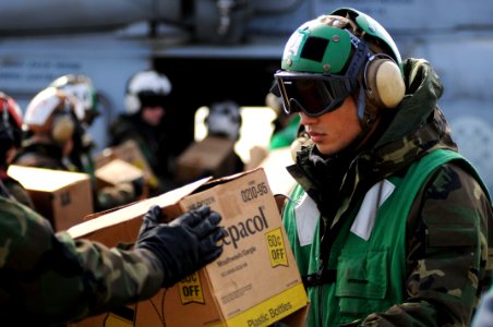 US Navy 110322-N-IC111-085 Aircrew Survival Equipmentman Airman Yuanfu Wu, from San Francisco, loads humanitarian assistance supplies onto an SH-60
