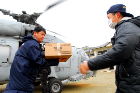 US Navy 110322-N-SB672-056 Japanese men unload humanitarian assistance supplies from an SH-60F Sea Hawk helicopter