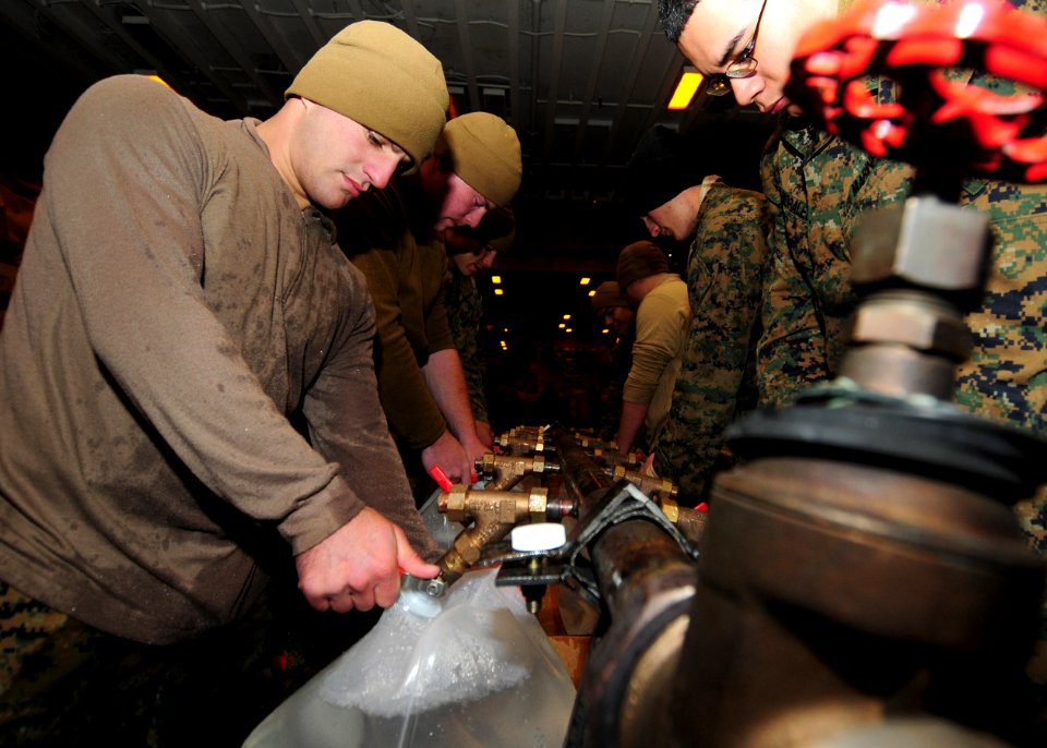 US Navy 110325-N-5538K-191 Marines assigned to the 31st Marine Expeditionary Unit (31st MEU) fill plastic containers with potable water in the hang