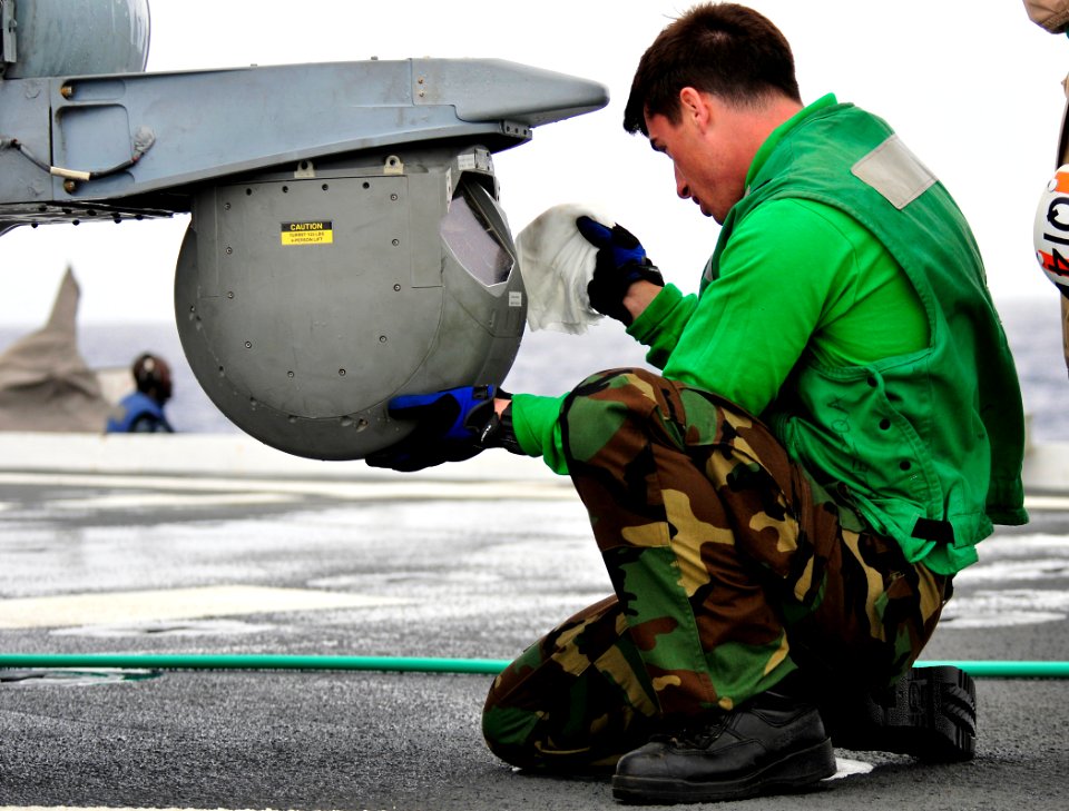 US Navy 110324-N-KB563-834 Aviation Electronics Technician Airman Robert Hunter cleans a forward looking infrared camera on an MH-60S Sea Hawk heli