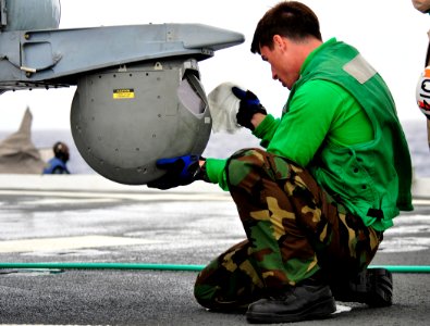 US Navy 110324-N-KB563-834 Aviation Electronics Technician Airman Robert Hunter cleans a forward looking infrared camera on an MH-60S Sea Hawk heli