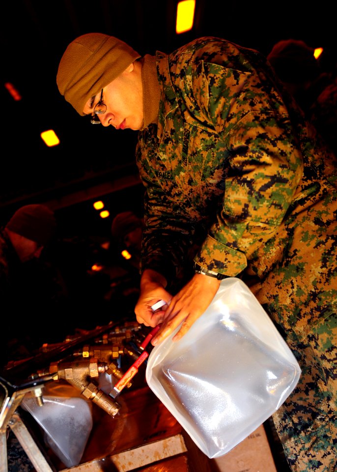 US Navy 110325-N-5538K-158 Lance Cpl. Erick Morales, assigned to the 31st Marine Expeditionary Unit (31st MEU), fills a plastic container with pota