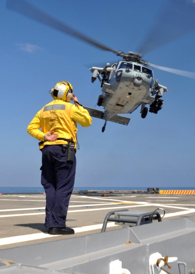 US Navy 110325-N-7293M-183 Aviation Boatswain's Mate (Handling) 2nd Class Matthew Kolb salutes an MH-60S Sea Hawk helicopter assigned to Helicopter