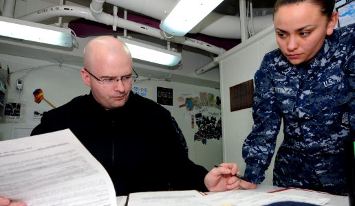 US Navy 110325-N-NB544-008 Legalman 2nd Class Michael Keehne and Legalman 2nd Class Jeneice Martinez review legal papers in the legal office aboard photo