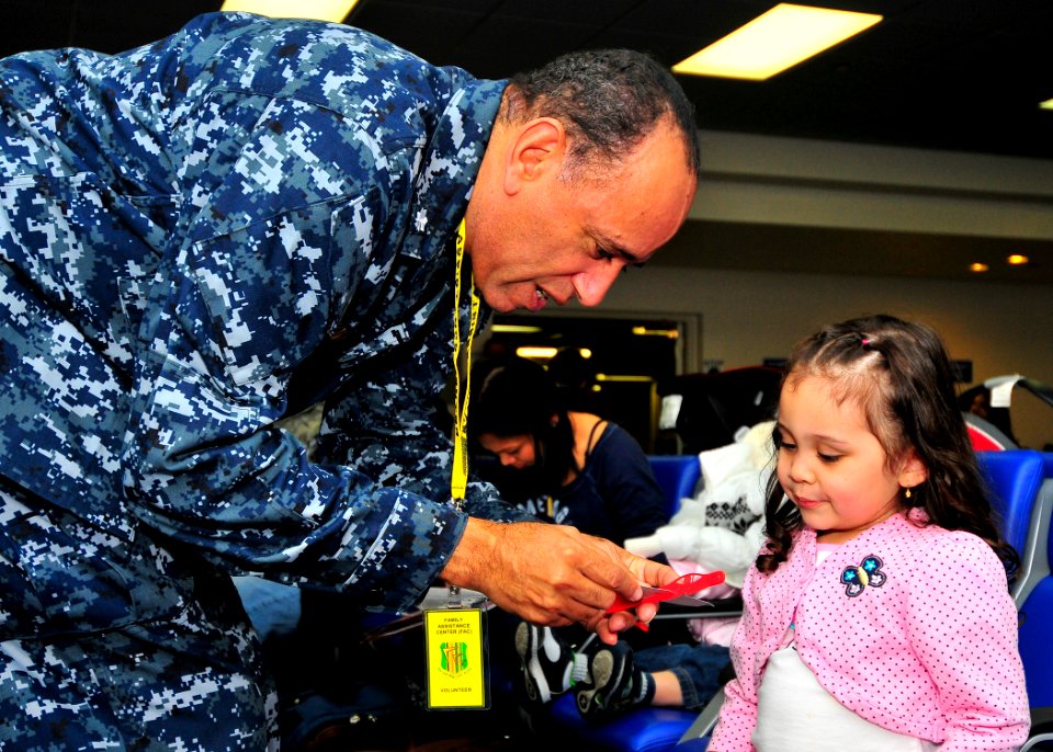 US Navy 110324-N-4044H-051 Cmdr. Robert J. Thomas entertains a child while her family waits for further instructions after passing through customs