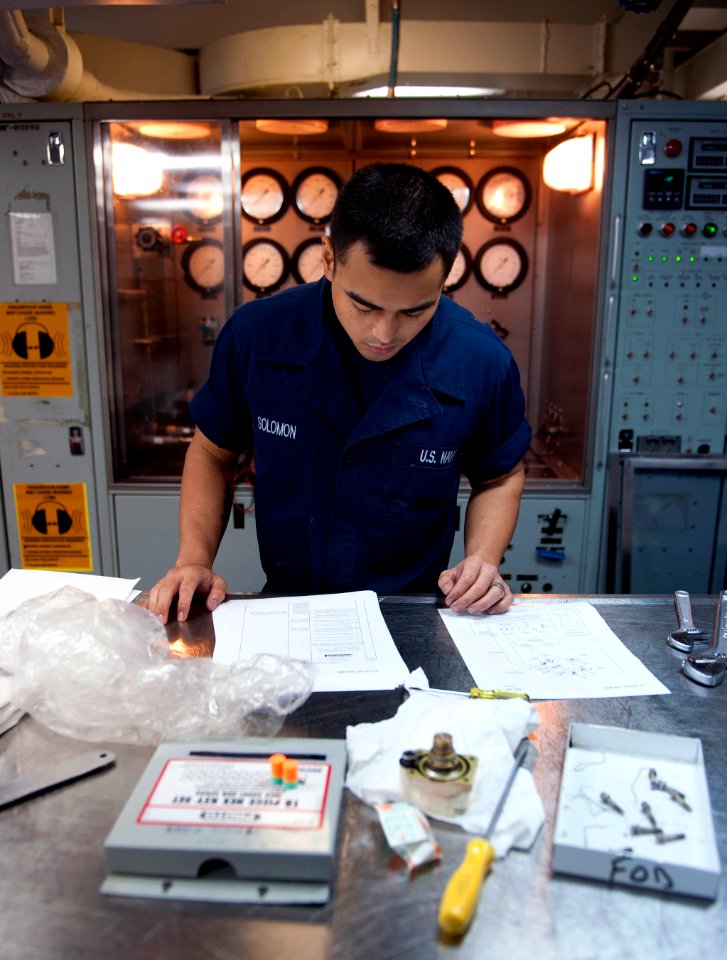 US Navy 110330-N-DR144-528 Aviation Structural Mechanic Airman James K. Solomon refers to technical publications before using a hydraulic test stan