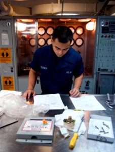 US Navy 110330-N-DR144-528 Aviation Structural Mechanic Airman James K. Solomon refers to technical publications before using a hydraulic test stan