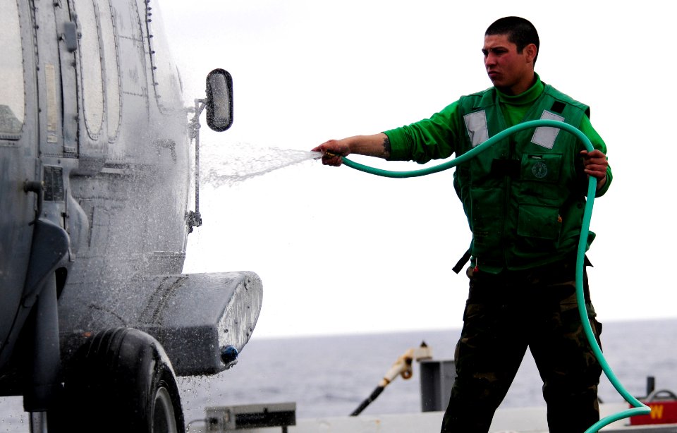 US Navy 110324-N-KB563-833 Aviation Electronics Technician Airman Christopher Garcia sprays down an MH-60S Sea Hawk helicopter to remove salt build