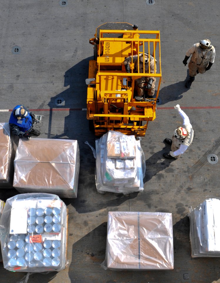 US Navy 110331-N-9950J-045 Sailors and Marines move supplies on the flight deck of the forward-deployed amphibious assault ship USS Essex (LHD 2) d
