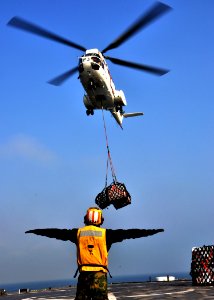 US Navy 110331-N-OM503-031 Boatswain's Mate 3rd Class Dennis Castro, signals the pilot of an SA-330J Puma helicopter as transports supplies aboard