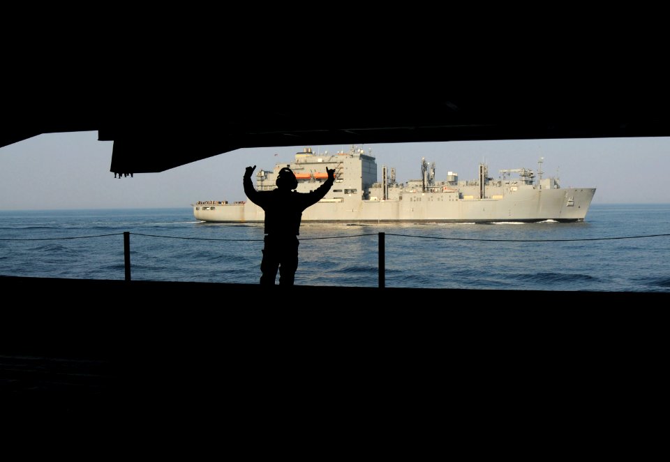 US Navy 110330-N-NB544-070 Aviation Boatswain's Mate (Handler) 2nd Class Luis Pena, from Santa Ana, Calif., signals as an elevator raises up to the