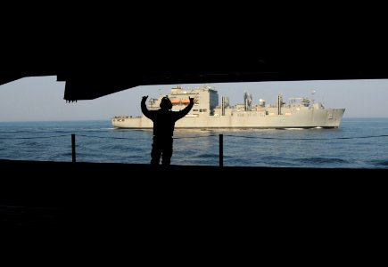 US Navy 110330-N-NB544-070 Aviation Boatswain's Mate (Handler) 2nd Class Luis Pena, from Santa Ana, Calif., signals as an elevator raises up to the