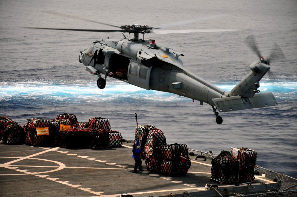 US Navy 110330-N-ZS029-488 A merchant marine prepares to attach a cargo net to an MH-60 Sea Hawk helicopter en route to USS Green Bay (LPD 20)