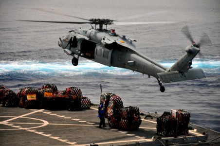 US Navy 110330-N-ZS029-488 A merchant marine prepares to attach a cargo net to an MH-60 Sea Hawk helicopter en route to USS Green Bay (LPD 20)