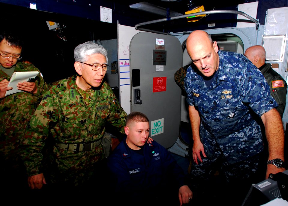 US Navy 110331-N-SB673-071 Rear Adm. Robert Girrier, right, and Operations Specialist 2nd Class Nick Suarez, center, explain operations supporting