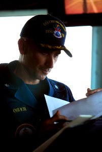 US Navy 110330-N-WP746-137 Cmdr. Justin Orlick reviews paperwork on the bridge aboard USS Chung-Hoon (DDG 93)