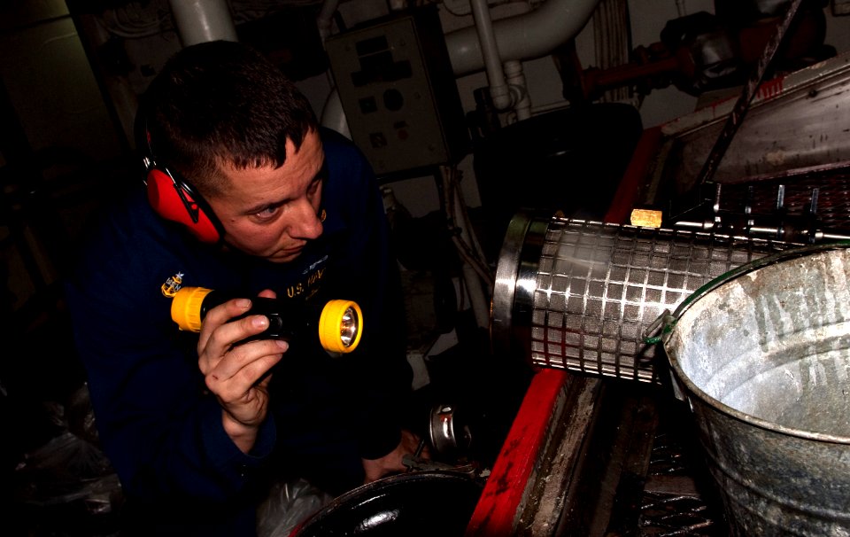 US Navy 110401-N-QP268-049 Senior Chief Ron Shasky inspects a lube oil strainer for the starboard main reduction gear aboard USS Whidbey Island (LS