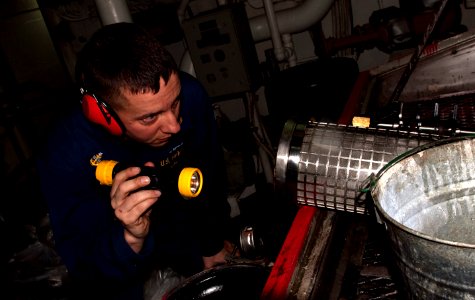 US Navy 110401-N-QP268-049 Senior Chief Ron Shasky inspects a lube oil strainer for the starboard main reduction gear aboard USS Whidbey Island (LS