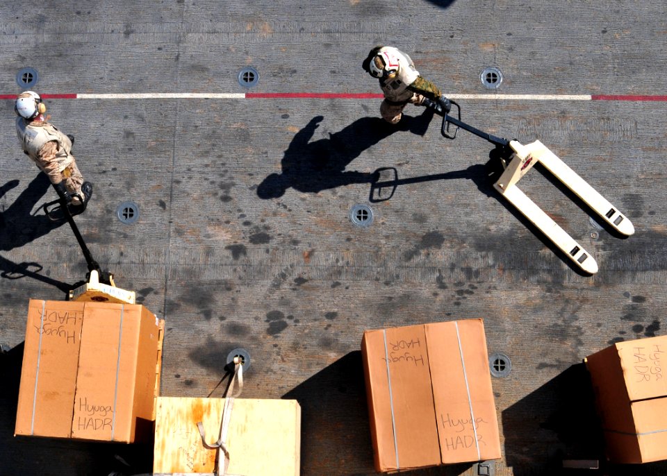 US Navy 110329-N-5538K-174 Marines position humanitarian assistance supplies on the flight deck of the forward-deployed amphibious assault ship USS