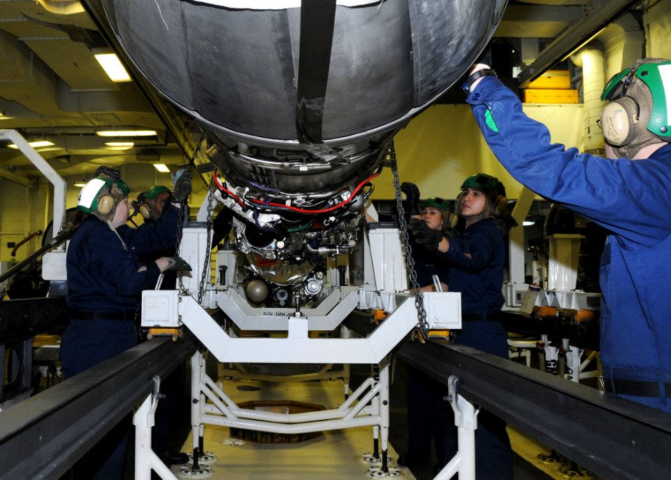 US Navy 110401-N-1004S-116 Sailors pull winching chains to lift an F404 jet engine out of its holding case aboard the aircraft carrier USS Ronald R