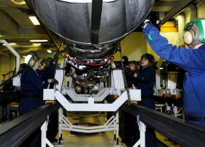 US Navy 110401-N-1004S-116 Sailors pull winching chains to lift an F404 jet engine out of its holding case aboard the aircraft carrier USS Ronald R