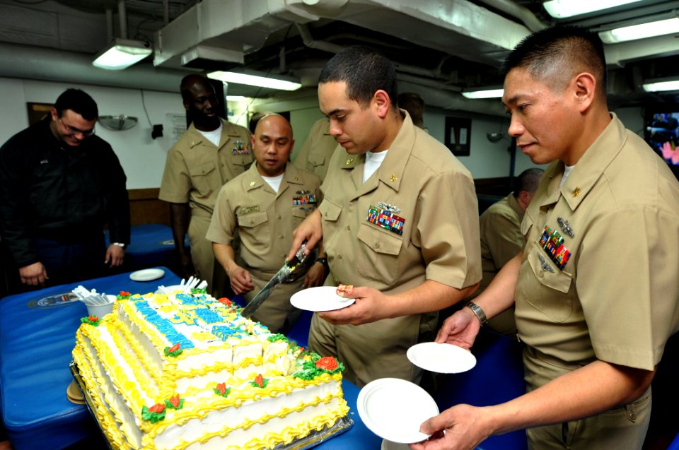 US Navy 110401-N-SF508-346 Chief Culinary Specialist Cruz Ayala, center, from Caguas, Puerto Rico, serves the cake during the 118th chief petty of