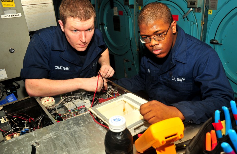 US Navy 110402-N-0074G-055 Electrician's Mate Fireman Erik W. Chatham, left, and Electrician's Mate Fireman Ian D. King troubleshoot an inoperable